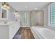 Bright bathroom featuring a double vanity, soaking tub with glass enclosure, and glass block window at 217 Myrtle Ln., Myrtle Beach, SC 29572