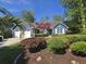 Charming blue home boasts an inviting entrance framed by lush landscaping, stone accents and a manicured lawn at 2333 Brick Dr., Longs, SC 29568