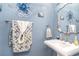 Stylish powder room featuring serene blue walls, decorative octopus art, pedestal sink, and decorative silver mirror at 487 Lantana Circle, Georgetown, SC 29440