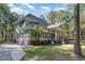 View of the home's side exterior featuring an attached garage, driveway, mature trees, and manicured lawn at 487 Lantana Circle, Georgetown, SC 29440