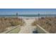 Sandy path to the beach, flanked by dunes and vegetation, offers serene seaside access for residents at 6001-5610 S Kings Hwy., Myrtle Beach, SC 29575