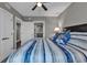 This cozy bedroom includes blue striped bedding, a ceiling fan, and a view of the en suite bathroom at 603 S Ocean Blvd. # 1101, North Myrtle Beach, SC 29582