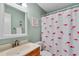 Bright bathroom features a flamingo shower curtain, white vanity and mirror, and light green wall at 6302 N Ocean Blvd. # G-3, North Myrtle Beach, SC 29582