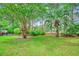 Grassy backyard with palm trees and shrubbery surrounded by trees at 8209 Timber Ridge Rd., Conway, SC 29526