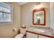 Bright half-bathroom with a wood-framed mirror, granite countertop, toilet, and a window for natural light at 8209 Timber Ridge Rd., Conway, SC 29526