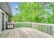 Outdoor deck with grill, white railings, and views of the lush green landscape and surrounding trees at 8209 Timber Ridge Rd., Conway, SC 29526