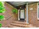 Close-up of the front door, showcasing brickwork, house number, and hanging plants at 8209 Timber Ridge Rd., Conway, SC 29526