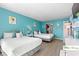 Spacious bedroom with two beds, desk, TV, and light wood floors under bright teal walls at 9550 Shore Dr. # 226, Myrtle Beach, SC 29572