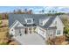 Two-story home featuring a stone and grey siding exterior, black roof, and a spacious driveway with yellow chairs on the front porch at 1004 Whooping Crane Dr., Conway, SC 29526