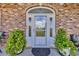 Front door of brick home with decorative glass and potted plants on a doormat at 1014 Academy Dr., Conway, SC 29526