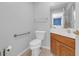 Bright powder room featuring tile floor, wood vanity, white counter, toilet, mirror, and grab bar at 1014 Academy Dr., Conway, SC 29526