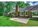 Brick home featuring a patio, manicured lawn, and a wall of windows overlooking a lush backyard at 107 Azalea Dr., Conway, SC 29526