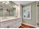 Bathroom featuring a double vanity, large mirror, wood-look flooring, and natural light at 107 Azalea Dr., Conway, SC 29526