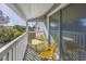 Inviting covered balcony with yellow metal table and chairs overlooking lush greenery at 1356 Glenns Bay Rd. # 208M, Surfside Beach, SC 29575