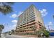 High-rise condo building with a parking garage surrounded by palm trees under a beautiful blue, partly cloudy sky at 1707 Perrin Dr. # 1003, North Myrtle Beach, SC 29582