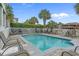 Community pool surrounded by lounge chairs, palm trees, and a privacy fence at 215-B S Dogwood Dr., Surfside Beach, SC 29575