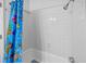 Bathroom with white tiled walls, colorful shower curtain, and shower head at 2701 Hillside Dr. S # 1, North Myrtle Beach, SC 29582