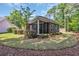 Exterior view of a brick house featuring a screened-in porch and lush landscaping at 455 Dornoch Dr., Pawleys Island, SC 29585