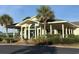 Clubhouse exterior featuring large windows, lush landscaping, a covered entrance, and a verdant palm tree at 4773 Wild Iris Dr. # 301, Myrtle Beach, SC 29577