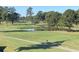Scenic view of the golf course, featuring mature trees, green fairways, a pond, and golfers at 4773 Wild Iris Dr. # 301, Myrtle Beach, SC 29577