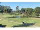 Scenic view of the golf course, featuring mature trees, green fairways, a pond, and a golf cart at 4773 Wild Iris Dr. # 301, Myrtle Beach, SC 29577