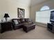 A carpeted living room featuring a leather sofa, a ceiling fan, and a window for natural light at 4773 Wild Iris Dr. # 301, Myrtle Beach, SC 29577