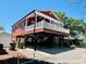 Stylish red home elevated on pilings, showcasing its unique design and covered parking area at 6001 - Z47 S Kings Hwy., Myrtle Beach, SC 29575