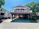 Charming raised red home featuring a white-railed porch and covered parking at 6001 - Z47 S Kings Hwy., Myrtle Beach, SC 29575
