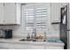 Close-up of kitchen sink, showcasing window with blinds and white cabinetry at 634 Cypress Ln., North Myrtle Beach, SC 29582