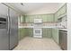 Functional kitchen featuring a stainless steel refrigerator, white appliances, and green cabinets at 68 Voyagers Dr., Pawleys Island, SC 29585