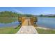 Scenic view of a private wooden dock extending into a serene lake with lush green trees and neighborhood homes in the background at 847 Flowering Branch Ave., Little River, SC 29566