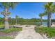 A serene view of a community fire pit surrounded by palm trees overlooking the lake, ideal for relaxation at 847 Flowering Branch Ave., Little River, SC 29566