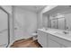 Bright bathroom featuring double sinks, wood-look floors, white cabinets and a glass shower door at 1011 Laconic Dr., Myrtle Beach, SC 29588