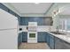 Well-equipped kitchen with white appliances, blue cabinets, and a subway tile backsplash at 1011 S Ocean Blvd. # 202, North Myrtle Beach, SC 29582