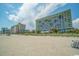 Expansive beach view in front of the multi-story condo building with lounge chairs in the sand at 1105 South Ocean Blvd. # 1008, Myrtle Beach, SC 29577
