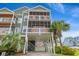 Three-story beach house with dual screened porches, covered parking, palm trees, and light-green siding at 113 B Vista Dr., Murrells Inlet, SC 29576