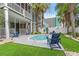 Relaxing outdoor pool area featuring Adirondack chairs, artificial turf, and mature palm trees for shade at 113 B Vista Dr., Murrells Inlet, SC 29576