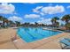 Large swimming pool with clear blue water, poolside lounge chairs, and a beautiful blue sky and clouds above at 1359 Peterson St., Myrtle Beach, SC 29577