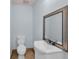 The half-bathroom features light blue walls, a white toilet, a white sink and vanity, and a decorative framed mirror at 1361 Turkey Ridge Rd. # C, Surfside Beach, SC 29575