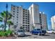 Multi-story condominium with a white facade, multiple balconies, and lush landscaping surrounded by a clear, blue sky at 2151 Bridge View Ct. # 2-803, North Myrtle Beach, SC 29582