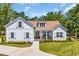 Charming farmhouse-style exterior featuring a manicured lawn, light blue shutters, and inviting front porch at 25 Northwoods Ct., Pawleys Island, SC 29585