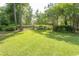 Expansive, level backyard with lush green grass and mature trees is enclosed by a black fence at 2600 Henagan Ln., Myrtle Beach, SC 29588