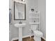 Charming half bathroom with pedestal sink, decorative mirror, and shelving offering both style and functionality at 302 Portofino Dr., Myrtle Beach, SC 29579