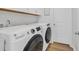 Modern laundry room featuring a GE washer and dryer set, white cabinets, and hardwood floors for a clean aesthetic at 302 Portofino Dr., Myrtle Beach, SC 29579