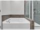 A pristine white tub sits beneath sleek tiling and a glass-enclosed shower, offering a luxurious bathing experience at 3119 Hannon Dr., Myrtle Beach, SC 29579
