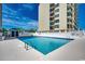 Inviting outdoor pool with sun loungers surrounded by a white fence with a view of the condo building at 3601 S Ocean Blvd. # 8-C, North Myrtle Beach, SC 29582