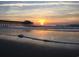 Beautiful beach sunrise with a pier silhouette and reflective water, ideal for morning strolls and serene views at 4008 Tupelo Ct., Conway, SC 29526