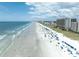 Aerial view showcases a vibrant beach with numerous beachgoers, colorful umbrellas, and oceanfront high-rise buildings at 492 Sun Colony Blvd., Longs, SC 29568