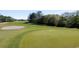 Beautiful golf course with a pristine green, a waving flag, and a sand bunker amid lush trees and blue skies at 492 Sun Colony Blvd., Longs, SC 29568