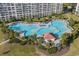 Aerial view of a large outdoor pool area with palm trees and lounge chairs by a resort at 5801 Oyster Catcher Dr. # 1214, North Myrtle Beach, SC 29582